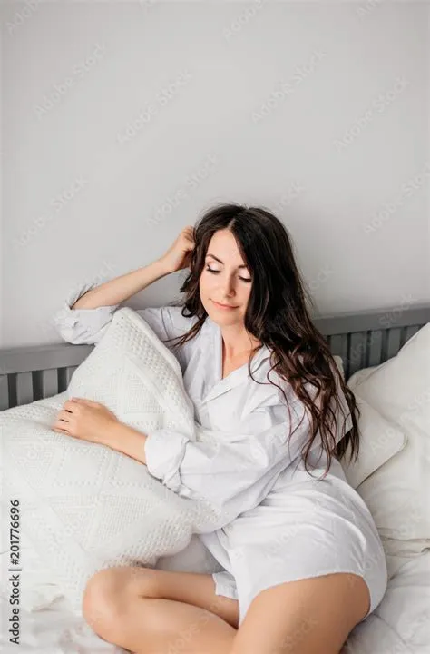 sexy young brunette woman wearing a white shirt on the bed at home ...