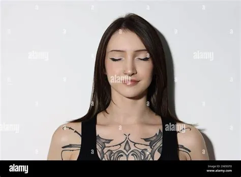 Portrait of beautiful tattooed woman on light background Stock Photo ...